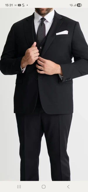 Svart slim fit kavaj från Dressmann - Säljer en svart kavaj från Dressmann i slim fit-modell. Klassisk design med spetsiga slag, tre framfickor och dekorativt innerfoder med stjärnmönster. Kavajen har knappar vid ärmslut och är perfekt för dig som vill ha en stilren och modern look.