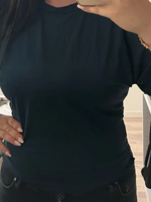 Svart basic t-shirt i bomull - En enkel svart t-shirt med rund hals och korta ärmar. Modellen är klassisk och passar till allt, tillverkad i mjuk bomull som känns skön mot huden. T-shirten har en normal passform och är helt utan mönster eller detaljer.