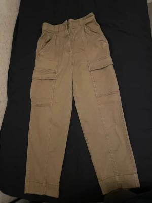 Beiga cargobyxor från H&M, strl 36 - Säljer ett par beiga cargobyxor från H&M i storlek.Tillverkade i bomull för en skön och avslappnad känsla. 