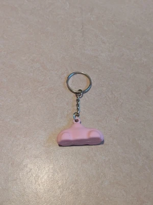 Nyckelring med rosa bil - Bilderna visar en jätte fin nyckelring med en rosa bil. Nyckelringen och den korta kedjan är av metall och den rosa bilen är av plast 