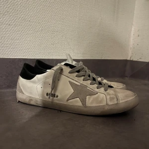 Golden Goose Superstar - Säljer ett par vita  Golden goose Superstar i storlek 43, funkar även som 44. Skorna är relativt fräscha, det ända felet är att sulan har spruckit vid hälen och vid sidan på ena skon. Men detta är ganska vanligt bland Golden goose. Våga buda på priset är inte hugget i sten👍🏻