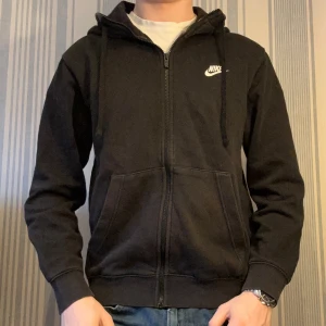 Svart nike zip hoddie - Svart Nike hoddie med zip. Hoddien har en väldigt bra passform och är i bra skick. Zip hoddien passar perfekt till vintern då den har en snygg luva och är väldigt bekväm. 