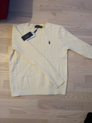 Vit kabelstickad tröja Polo Ralph Lauren - Vit kabelstickad tröja från Polo Ralph Lauren i storlek S helt nytt skick med taggarna fortfarande på inga defekter perfekt till alla väder 