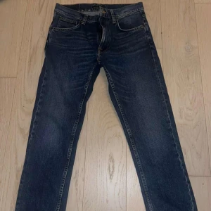 Nudie Jeans Lean Dean Indigo Exile 31/30 - Snygga mörkblå Nudie Jeans i modellen Lean dean. De är i färgen Indigo Exile för att vara exakt. Klassisk femficksdesign, orangea sömmar och smal passform. Tillverkade i 99% bomull och 1% elastan för lite stretch. Perfekta för dig som gillar jeans som sitter som de ska med en slimfit passform som får dig att känna dig grish. De har använts ett fåtal gånger och tvättats nån gång, fortfarande i prima skick och har tagits hand om väl. Skriv om ni har någon fundering😆