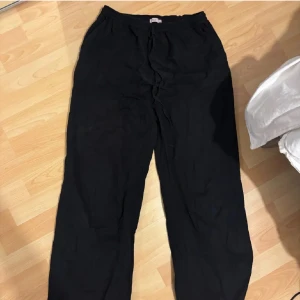 Svarta vida linnebyxor med snörning - Snygga svarta linnebyxor med avslappnad passform och vida ben. Byxorna har låg midja med elastisk linning och snörning för extra komfort. Perfekta för en chill och stilren look, lätta att matcha med crop tops eller oversized skjortor. 