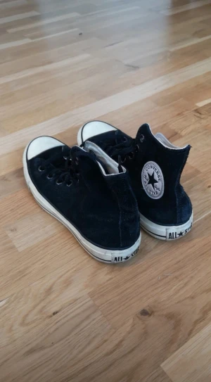 Svarta Converse - Klassiska svarta Converse All Star med högt skaft. Skorna har vit sula, rund tå och Snörning. Med Converse-logga på sidan. Skorna är i använt men ändå bra skick, se bilder