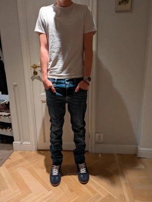 Mörkblå slim jeans - Säljer ett par mörkblå jeans med tvär snygg tvätt och klassiska fem fickor. Jeansen har normal passform, raka ben och låg midja. Perfekta för dig som gillar en stilren look med lite streetkänsla. Materialet är slitstarkt denim i bomull.