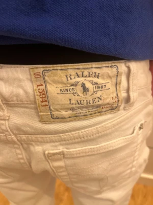 Vita jeans från Ralph Lauren - Snygga vita jeans från Ralph Lauren med klassisk patch bak i midjan. Modellen har raka ben, fem fickor och normal passform. Tillverkade i mjukt bomullstyg som ger en skön känsla. Perfekt för dig som gillar stilrena och fräscha jeans.