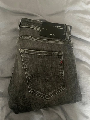 Replay Joe straight fit jeans grå - Snygga Replay Joe straight fit jeans i tvättad grå färg med klassisk femficksdesign och diskreta slitningar. Jeansen har normal passform och raka ben, tillverkade i slitstarkt denim med Replay-logga på bakfickan. Perfekt för dig som gillar stilrena och tidlösa jeans. Bra skick men har ett rip där bak( syns på bild 5),själv tycker jag att det inte syns på. Säljer pga för små
