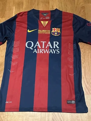 Retro 2014/15 FC Barcelona home  - Säljer en officiell FC Barcelona matchtröja från finalen i Berlin 2015 med Neymar Jr och nummer 11 på ryggen. Tröjan har breda marinblå och röda ränder, gula detaljer och tryck, samt Qatar Airways och UNICEF-loggor. Tillverkad i lätt polyester med Dri-FIT-teknologi. kan snackas om priset. Om de tryckt: Produkten rekommenderas att handtvättas för att inte skada trycket, men om du använder en tvättmaskin, tvätta tröjan i 30° grader. Vänd alltid tröjan ut och in så att trycket inte skadas. Observer