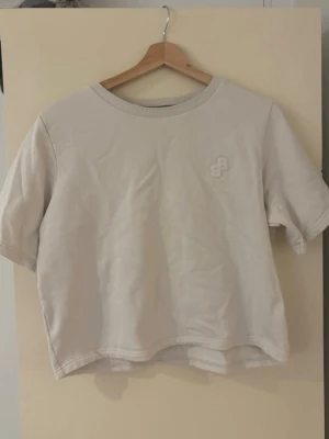 Vit t-shirt från BOSS med broderad logga - Snygg vit t-shirt från BOSS i bomull med broderad BOSS-logga på bröstet. Klassisk rund halsringning med ribbad kant och normal passform. Perfekt till jeans eller shorts för en clean och stilren look.