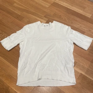 Vit ribbad topp från lager  157 XS - Säljer en enkel och stilren vit topp från lager 157 i storlek XS. Toppen har ribbade kanter vid hals, ärmslut och nederkant samt korta armar. Toppen sitt tight vid mot kroppen nere vid mudden