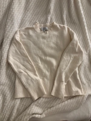 Vit stickad tröja - Klassisk vit stickad tröja från Ralph Lauren med rund halsringning och breda ribbade muddar vid ärmslut och nederkant. Perfekt till lager på lager och enkel att matcha med allt. Supermjuk och skön att bära.