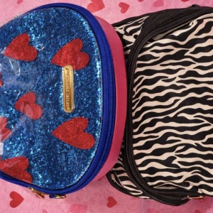 Två små nesesärer : zebra & glitterhjärtan med  nya hårnålar två spännen  fint  - Säljer två nessesärer ! En i svartvitt zebramönster  bägge med dragkedja och en blå glittrig väska med rosa hjärtan och guldfärgad Betsy Johnson-detalj. Perfekta för smink eller småprylar. Båda har unik design och  skiner  extra hemma. Ena har en fick a med innespegel  och något tror två spännen medföljer har förvarats  endast spänne i dessa. Och d har glömts  bort.  Mkt fint skick och fräscha 