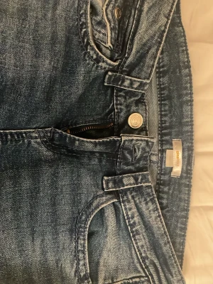 Blå jeans med coola bakfickor  - Säljer ett par blå jeans från Gina Tricot. Klassisk femficksmodell med dragkedja och knapp framtill. Skriv/DM för fler bilder. 