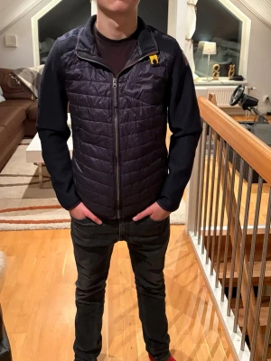 Mörkblå quiltad jacka från Parajumpers - Säljer en mörkblå jacka från Parajumpers med quiltad front och rygg, samt släta ärmar. Jackan har dragkedja och en gul detalj vid kragen. Perfekt för dig som gillar stilren och sportig look. Cardiganen har inga fläckar eller något skadligt på den och den är använd ett fåtal gånger, skriv vid minsta fundering🙌🏻🙌🏻