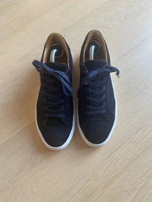 Mörkblå mockasneakers med vit sula - Snygga mörkblå sneakers i mocka med klassisk vit sula och rund tå. Skorna har snörning och en stilren design som passar till det mesta. Insidan är ljusbrun och materialet känns mjukt och lyxigt.stor i storleken 