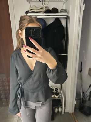 Blus med knyte  - En svart stilren festlig men även vardags blus. Det är spets material på blusen med två stycken knyten en som man inte ser bara så blusen ska sitta men inget måste att användas. Blusen har en v-ringning och lite smått volang vid nedre delen