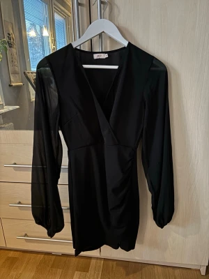Svart klänning  - Supersnygg svart klänning som är v-ringad med långa ärmar i tunt tyg. Från Nelly i storleken XS, passar även S. Aldrig använd så i nyskick💕