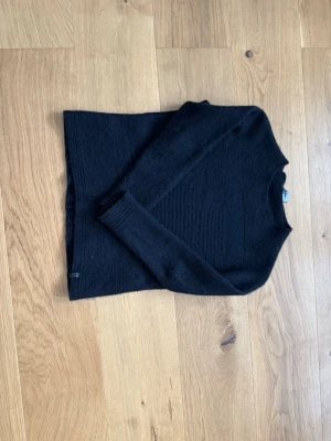 Svart stickad tröja från Diesel - Säljer en svart stickad tröja från Diesel med enkel och clean design. Tröjan har lång ärm och rund halsringning, perfekt för lager på lager under kyliga dagar. Diskret Diesel-logga i nederkant. Passar dig som gillar stilrena basics.