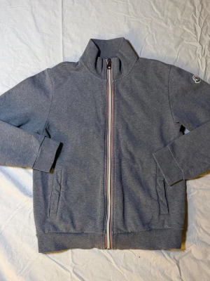 Grå Moncler Cardigan XS - Säljer en Moncler cardigan i grå färg, storlek XS, i mycket bra skick. En stilren och lyxig cardigan som fungerar perfekt som lätt jacka eller mellanlager året runt.  Plagget är i väldigt fint skick. Alla lappar är bortklippta, men äkthetsbevis finns tydligt med på sista bilden, vilket gör köpet tryggt. Klassisk Moncler-design som funkar till både clean outfits och mer avslappnad streetwear.  Mått: Undersida: 38 cm Längd: 59 cm  • Märke: Moncler • Färg: Grå • Storlek: XS • Skick: Mycket bra • 10