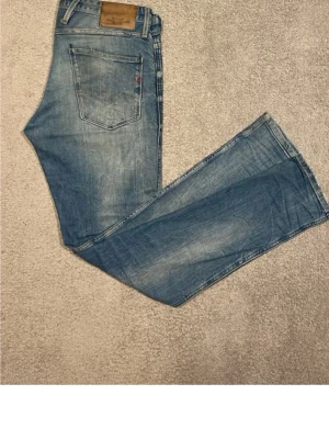 Replay jeans  - Snygga ljusblå Replay Anbass jeans med klassisk femficksmodell och slitna detaljer. Jeansen har normal passform och är tillverkade i mjukt bomullsjeansmaterial. Perfekta för dig som gillar en avslappnad men trendig look.