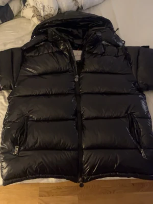 Moncler Maya - Säljer en svart Moncler Maya i storlek L. Jackan har glansig finish, huva, två dragkedjefickor och klassisk Moncler-logga på bröstet. Perfekt för kalla dagar och riktigt snygg streetstil. Jackan är vadderad och har dragkedja framtill. Tveka inte på att ställa en fråga eller två!❤️🙏