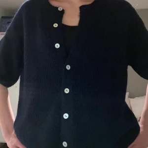 Mörkblå stickad kofta med knappar - Säljer en mörkblå stickad kofta med korta ärmar och vita knappar framtill. Koftan köptes på Gina tricot men endast använd 1 gång🥰
