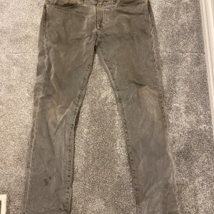 Levi's 511 grå jeans W32 L32 - Säljer ett par grå Levi's 511 jeans med klassisk femficksdesign och smal passform. Jeansen har en snygg, något urtvättad look och är tillverkade i slitstarkt bomullstyg. Perfekta för dig som gillar en stilren och enkel vibe.