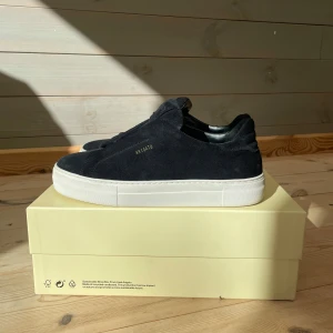 Axel Arigato Clean 360 Laceless - Stilrena svarta sneakers från Axel Arigato i mocka med vit platt sula. Diskret logga i guld på sidan. Använd fåtal gånger, så skicket är nästan som nya. Pris går självklart att diskuteras!😁