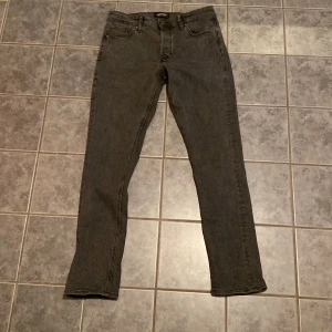 Grå jeans från Jack & Jones - Snygga grå jeans från Jack & Jones med klassisk femficksdesign och raka ben. Jeansen har en mörkgrå tvätt och är tillverkade i mjukt denimtyg.