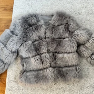 Grå fluffig pälsjacka - Säljer en supermjuk och fluffig grå pälsjacka med breda paneler och lång ärm. Jackan har en lyxig känsla och är fodrad på insidan för extra komfort. Perfekt för dig som vill sticka ut och hålla dig varm under kalla dagar.