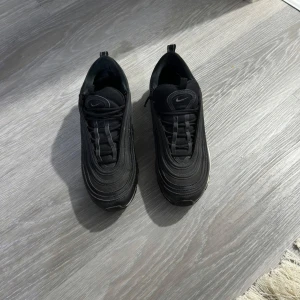 Nike Air Max 97 svarta sneakers - Svarta Nike Air Max 97 sneakers men reflex vid natt tid, använd några gånger förra året. Storlek 41 Nike loggan vid baksidan och har lite svarta träck på bubblorna 