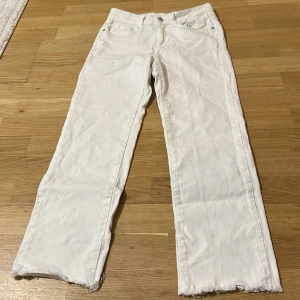 Vita raka jeans från Uniqlo - Vita jeans  med rak passform och råa, fransiga benslut. Klassisk femficksmodell med knapp och dragkedja i midjan. Tillverkade i kraftig bomullsdenim för en clean look.