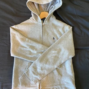 Polo Ralph Lauren Zipper - Säljer en grå Polo Ralph Lauren Zip-Up i kids storlek L. Tröjan är i väldigt bra skick. Priset kan diskuteras.