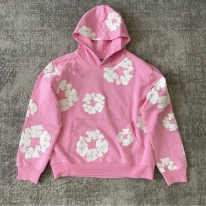 Rosa hoodie med vita blommor - Säljer en rosa hoodie med vita blommönster över hela tröjan. Tröjan har huva, magficka och långa ärmar. Perfekt för dig som gillar färg och vill sticka ut lite extra finns slla storlekar.