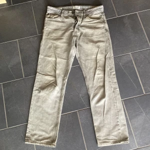 Grå jeans Relaxed/Chris 29/30 - Snygga grå jeans från Jack &jones i rak modell. Byxorna har klassisk femficksdesign, normal passform och raka ben. Tillverkade i mjukt jeanstyg som ger en avslappnad vibe. Perfekta för dig som gillar en enkel och stilren look. Ganska slitna och därför just priset. 