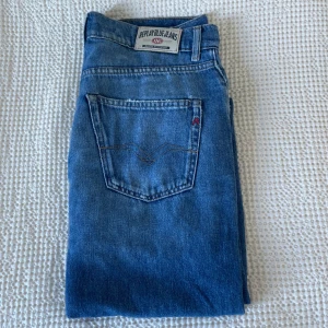 Blå jeans från Replay - Säljer ett par klassiska blå jeans från Replay med snygga detaljer på bakfickan och tydlig Replay-logga. Jeansen har en standard passform och är tillverkade i slitstarkt denimtyg. Perfekta för dig som gillar en tidlös och enkel stil.