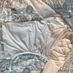 Ljusbeige långärmad kortklänning - Snygg ljusbeige tröja med långa ärmar och lätt rynkade detaljer vid sidan. Tröjan har en enkel, stilren design och är tillverkad i ett mjukt, stretchigt material som sitter bekvämt på kroppen.