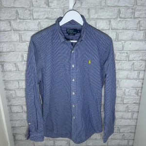 Ralph Lauren skjorta - Blårutig Ralph Lauren skjorta i modellen Slim Fit. Använd väldigt sparsamt, i mycket bra skick. Sitter snyggt och är lätt att matcha både till vardags och mer uppklätt. Hör av dig vid intresse🙌