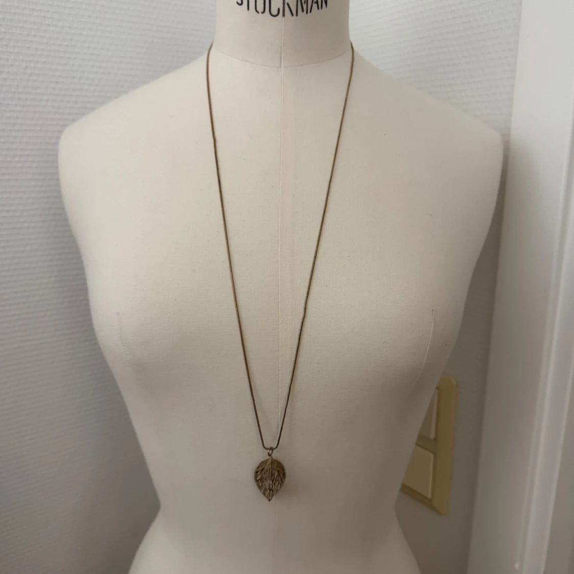 Långt halsband med bladberlock i guld