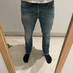 Nudie Jeans Grim Tim - Tja säljer ett par sjukt snygga nudie jeans. Modellen är grim Tim och storleken är 33/32. Modellen på bilden är 187cm.  (Omsydda vid vänstra knäet)Hör av dig vid frågor! 