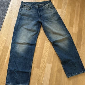 Blå wide jeans från Weekday - Säljer helt nya  jeans från Weekday med breda ben och klassisk femficksdesign. Jeansen har en snygg tvätt med ljusare partier framtill och baktill, samt hög midja. Materialet är robust denim i bomull. Perfekta för en avslappnad och trendig look. Har bara tagit ur dom ur förpackningen och provat så helt nya.