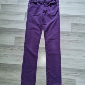 Lila jeansbyxor från Cubus, stl 164 - Snygga lila jeansbyxor från Cubus i storlek 164. Klassisk femficksmodell med raka ben och normal passform. Byxorna har knapp och dragkedja framtill samt bälteshällor. Perfekta för dig som vill sticka ut med färg.