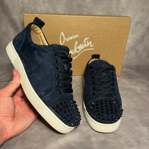 Christian Louboutin sneakers - Mörkblå sneakers i mocka från Christian Louboutin med vita sulor och ikonisk röd undersida. Skorna är i storlek EU 40 men sitter som 41-42. Skicket är otroligt bra använda 1-3 gånger. Box dustbags extra snören fås med. Äkta vara inget trams kvitto finns.