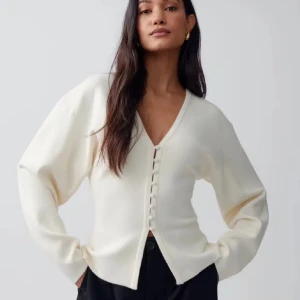 Vit kofta med v-ringning och knappar - Säljer en stilren vit kofta med v-ringning och dekorativa knappar framtill. Koftan har långärmad design och är tillverkad i ett mjukt, stickat material. Perfekt för lager-på-lager och enkel att matcha med olika outfits. Använd 2 ggr