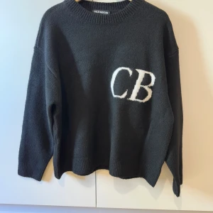 Svarta mjukisbyxor Cole Buxton S - Svarta mjukisbyxor från Cole Buxton i storlek S. Byxorna har en relaxed passform och är tillverkade i mjukt material. De har en vit CB-logga broderad på ena benet och resår i midjan för extra komfort.