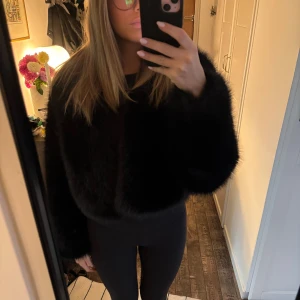 Svart pälsjacka croppad modell - Säljer en svart, croppad pälsjacka med lång ärm. Jackan har en fluffig och mjuk känsla, perfekt för dig som vill sticka ut med en trendig look. Enkel och stilren design utan synliga knappar eller dragkedja.❤️‍🔥