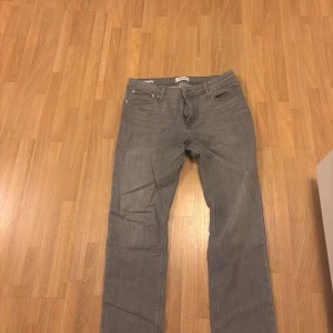 Grå jeans från Jack & Jones, storlek 34/32 - Säljer ett par grå jeans från Jack & Jones, modell Regular Fit Clark. Klassisk femficksdesign, raka ben och normal passform. Ingen regelbunden användning. Nypris vid köp 800 kr. 