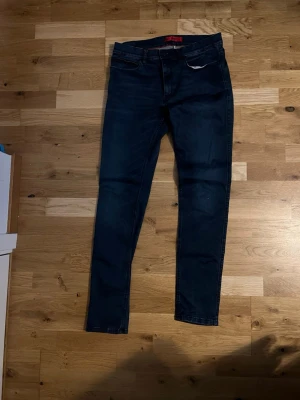 Mörkblå skinny jeans från Hugo Boss - Snygga mörkblå skinny jeans från Hugo Boss med klassisk femficksdesign och diskreta slitningar. Jeansen har normal midja och är tillverkade i mjukt bomullsmaterial med stretch för extra komfort. Passar perfekt till en avslappnad men stilren look. Aldrig använd, inga defekter, materialet liknar Replay hyperflex extremt på grund av bomull och denim mixen , nypris på Hugo boss jeans ligger runt 1799 , skriv vid funderingar 